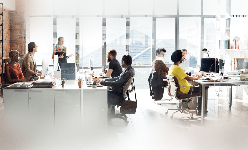 Diversidade. Na imagem podemos ver uma sala de escritório com várias pessoas trabalhando nela. 