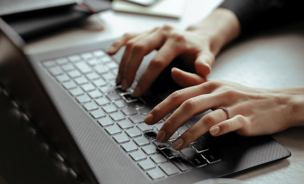 deficiência. Imagem de uma mão branca e feminina usando um notebook.