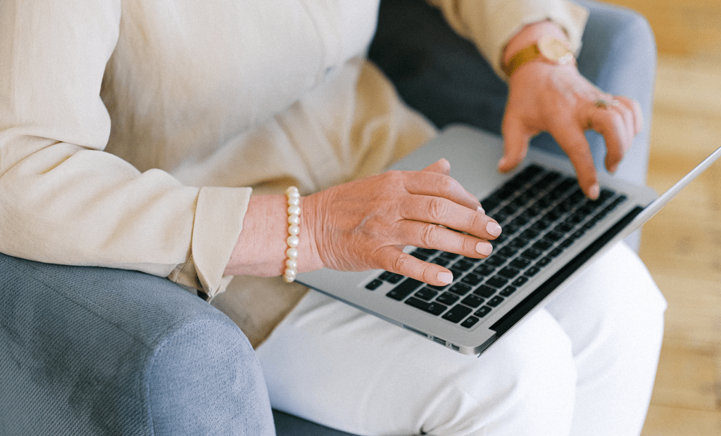 Conscientização. Imagem de uma mão idosa e feminina mexendo no notebook.