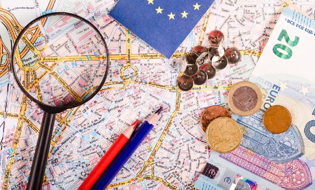 Turismo. Imagem de um mapa com uma lupa e umas notas e moedas. 