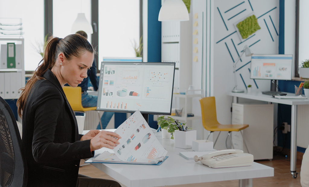 Mulher trabalhando em um escritório e observando papéis com gráficos