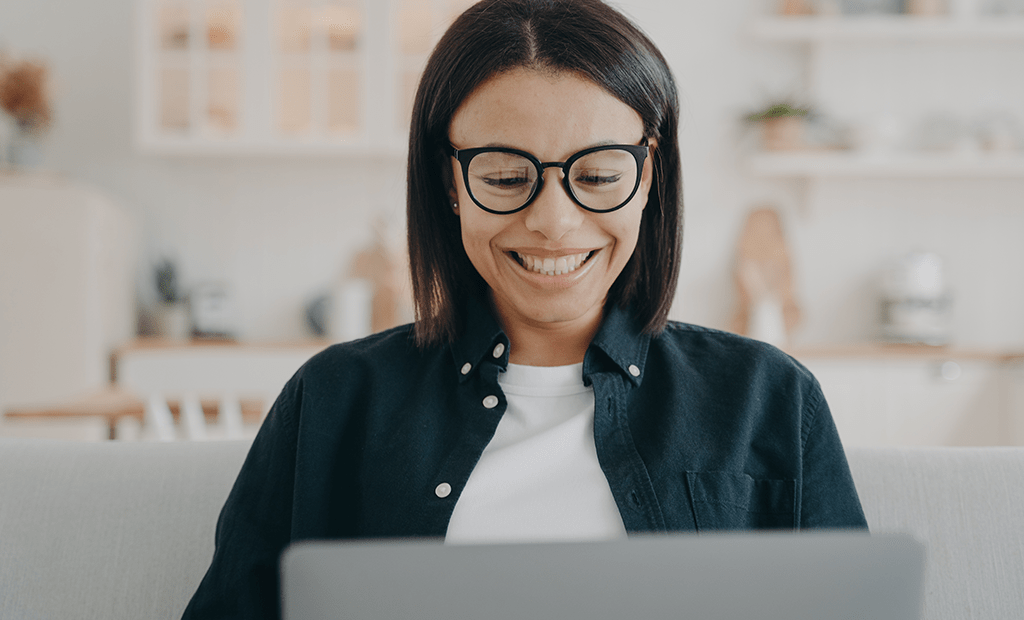 Mulher sorri enquanto mexe no computador