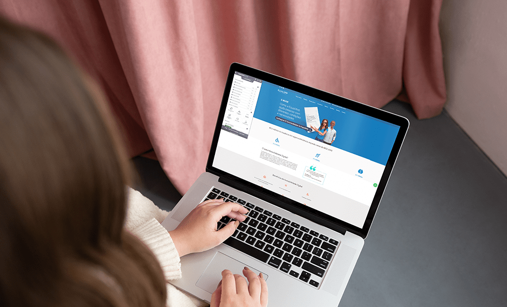 Tecnologia. Imagem de uma mulher branca de costas mexendo no computador com o site da EqualWeb aberto.
