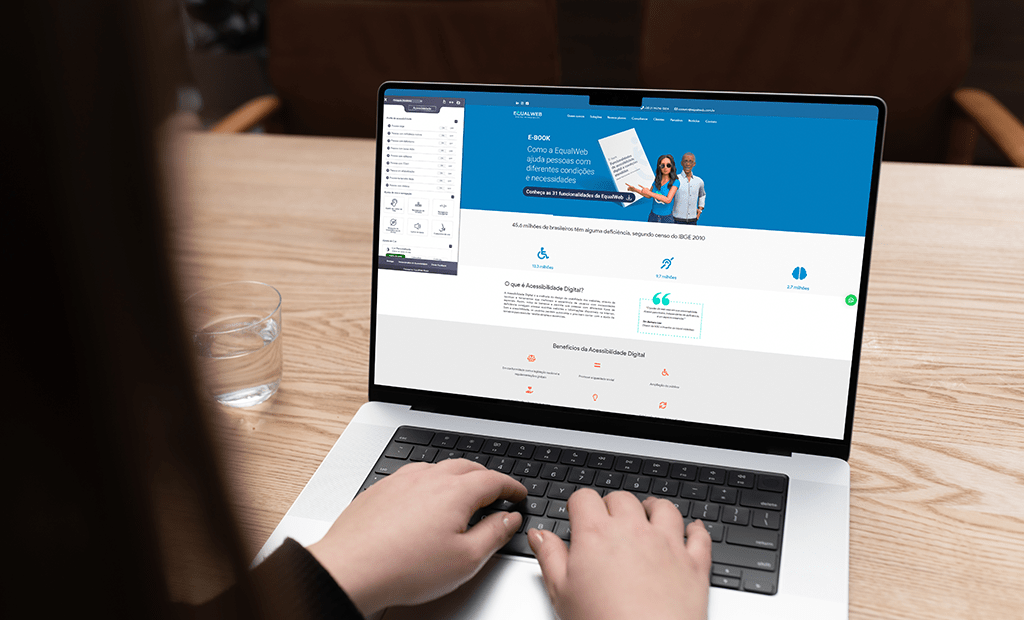Acessível. Imagem de uma tela de computador aberta com o site da Equalweb em primeira página. Na imagem também aparece uma mão feminina teclando no computador.