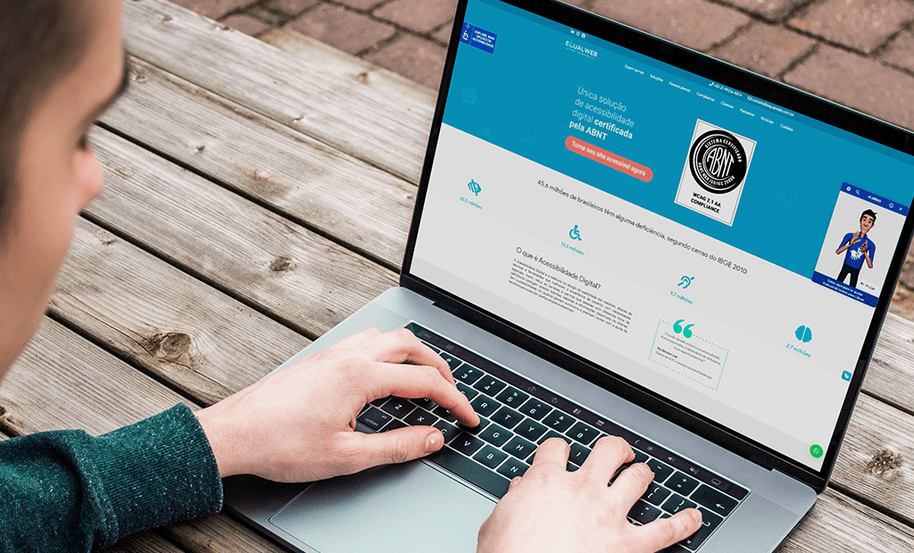 Libras. Imagem de uma mão branca mexendo em um notebook com osite da Equalweb aberto.