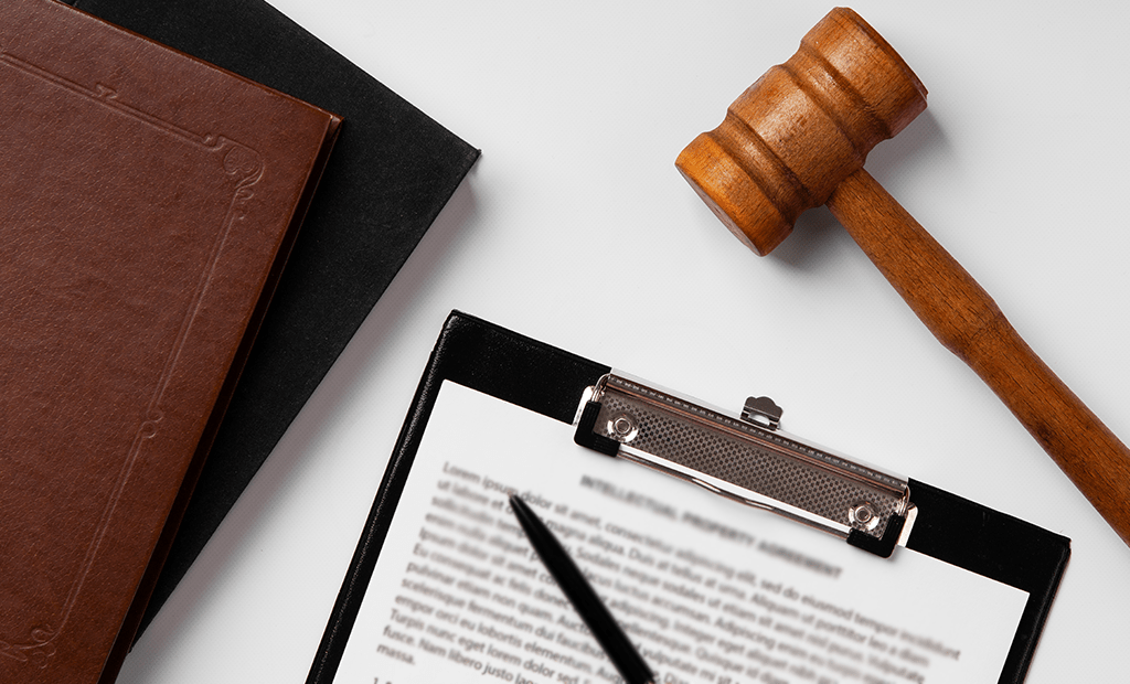 Leitores de tela. Martelo de juiz ao lado de uma prancheta com um documento e uma caneta sobre a mesa.