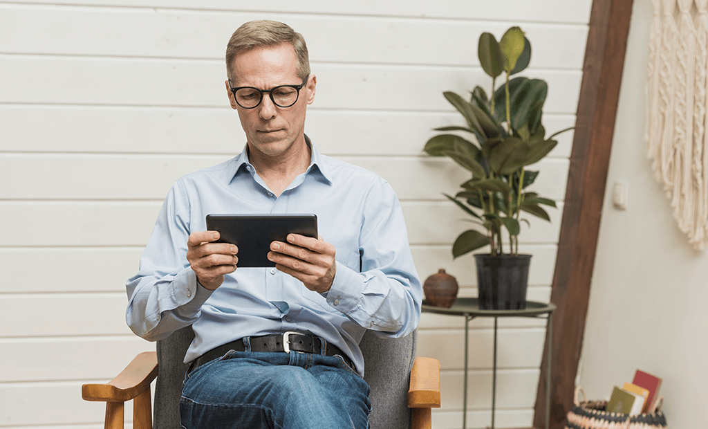 Autismo. Pessoa sentada lendo um tablet em ambiente aconchegante com plantas ao fundo
