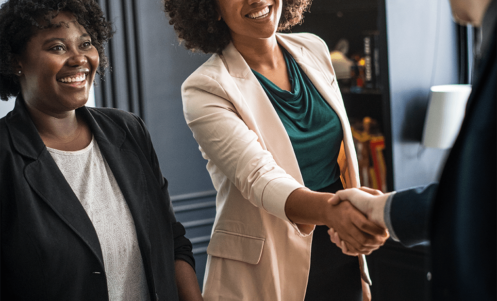 Overlays. Duas mulheres sorrindo; uma delas está apertando a mão de outra.