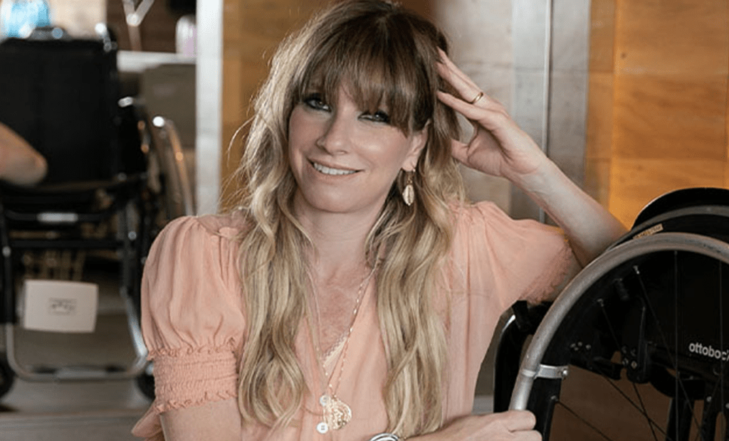 Acessibilidade digital Foto da Andrea Schwarz ao lado da sua cadeira de rodas