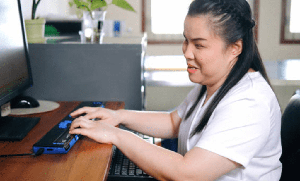 Tecnologias assistivas. Menina com deficiência visual usando o computador
