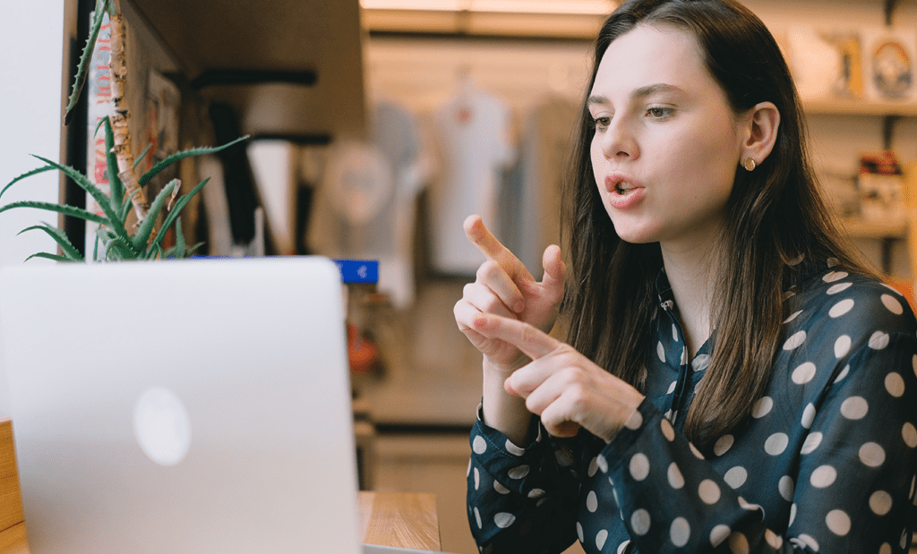 Acessibilidade digital; Na imagem temos uma mulher branca de cabelos longos gesticulando em frente ao computador.