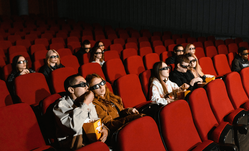 entretenimento. Imagem de uma sala de cinema com algumas pessoas assistindo filme.